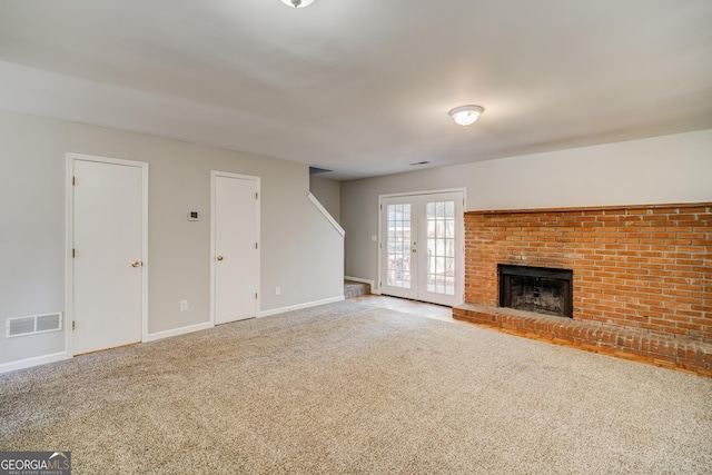 unfurnished living room with carpet, a fireplace, and french doors