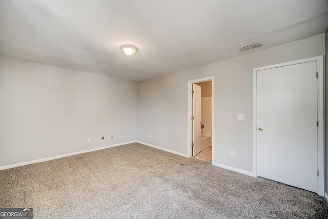 unfurnished bedroom with light colored carpet and ensuite bath