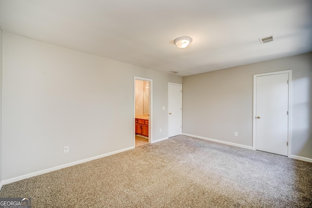 unfurnished bedroom featuring connected bathroom and light colored carpet