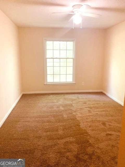 carpeted spare room with ceiling fan