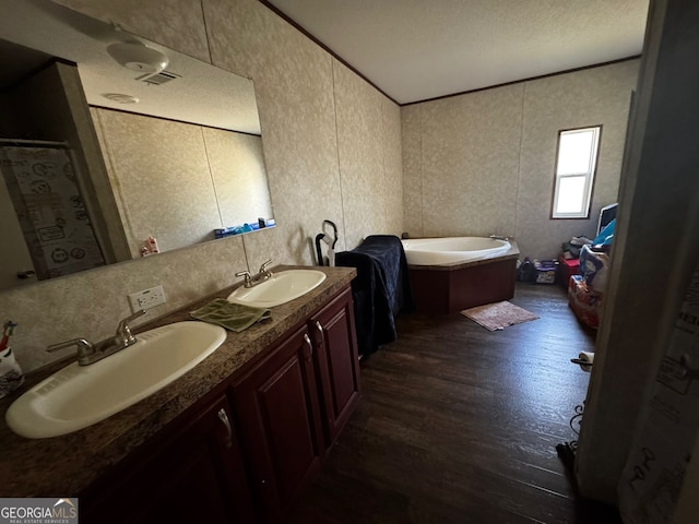 bathroom with a washtub, hardwood / wood-style flooring, crown molding, vanity, and a textured ceiling