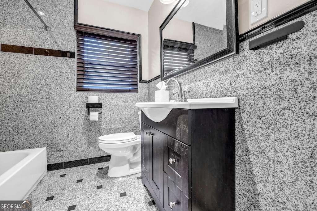 bathroom featuring a tub to relax in, vanity, toilet, and tile walls