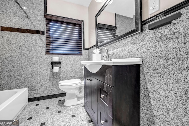 bathroom featuring a tub to relax in, vanity, toilet, and tile walls