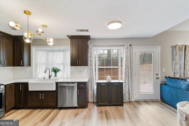 kitchen with sink, hanging light fixtures, light hardwood / wood-style flooring, stainless steel appliances, and backsplash