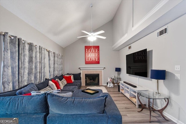 living room with hardwood / wood-style flooring, ceiling fan, high vaulted ceiling, and a fireplace