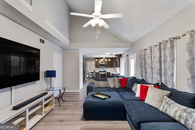 living room featuring ceiling fan, high vaulted ceiling, and light hardwood / wood-style floors