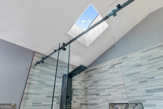 room details featuring a shower with door and a textured ceiling