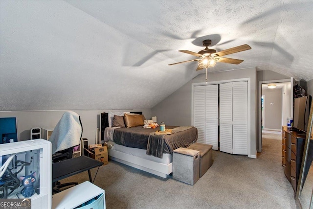 carpeted bedroom featuring ceiling fan, lofted ceiling, a textured ceiling, and a closet