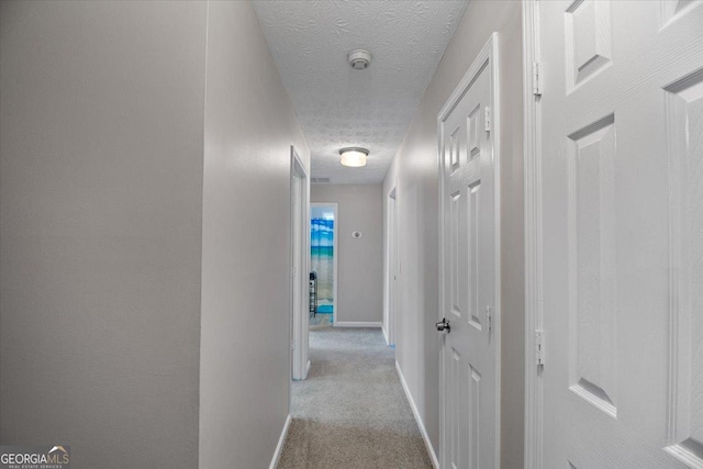 hall with light carpet and a textured ceiling