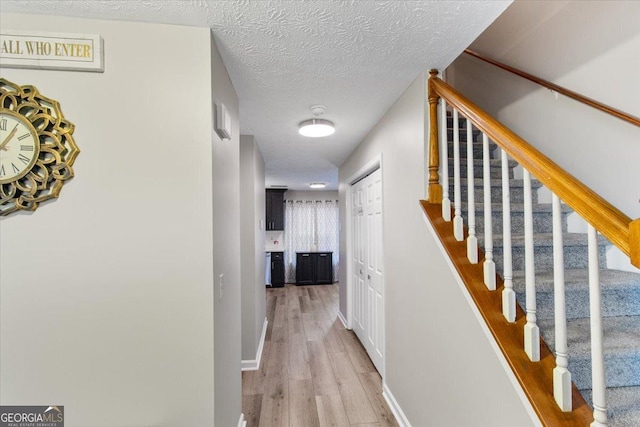 hall with light hardwood / wood-style flooring and a textured ceiling