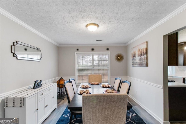 dining room with ornamental molding, dark wood-type flooring, and a textured ceiling