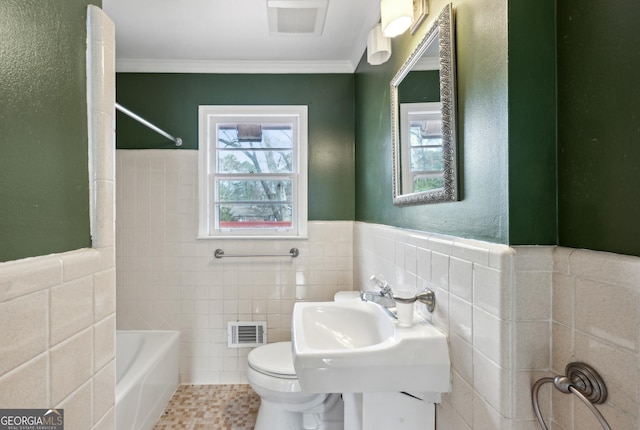 full bathroom featuring toilet, sink, crown molding, tile walls, and shower / washtub combination