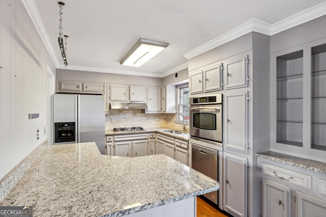 kitchen with appliances with stainless steel finishes, sink, decorative backsplash, ornamental molding, and light stone countertops