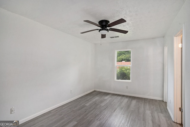 unfurnished room with ceiling fan, light hardwood / wood-style flooring, and a textured ceiling