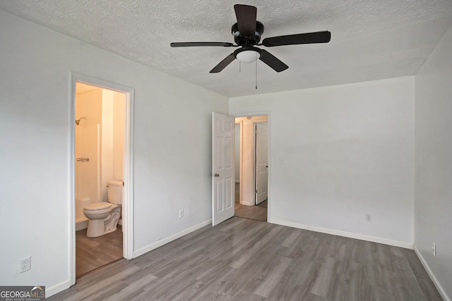 unfurnished bedroom with ceiling fan, ensuite bath, a textured ceiling, and light wood-type flooring