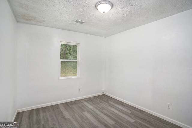 unfurnished room with hardwood / wood-style floors and a textured ceiling