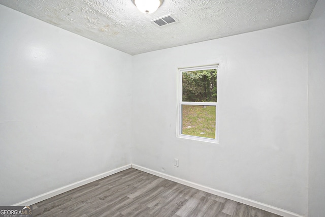 unfurnished room featuring hardwood / wood-style flooring and a textured ceiling