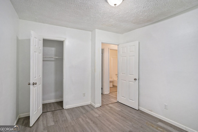 unfurnished bedroom featuring a textured ceiling, a closet, and light wood-type flooring