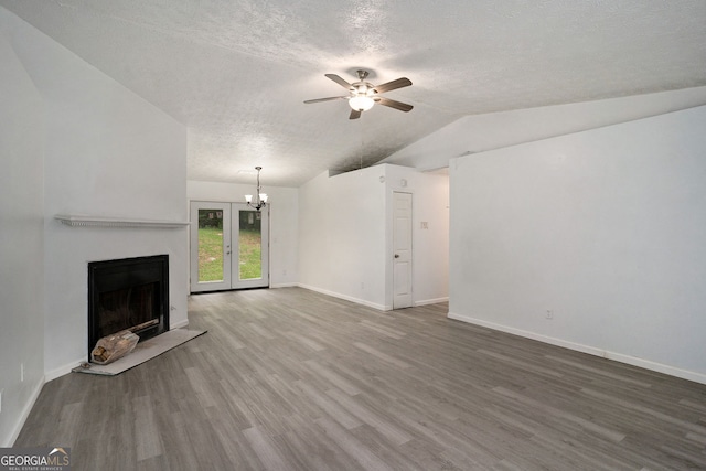 unfurnished living room with lofted ceiling, ceiling fan with notable chandelier, wood-type flooring, and a textured ceiling