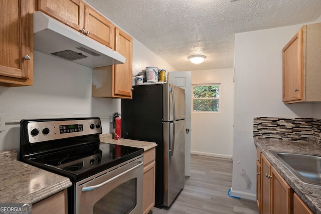 kitchen featuring sink, tasteful backsplash, a textured ceiling, stainless steel appliances, and light hardwood / wood-style floors