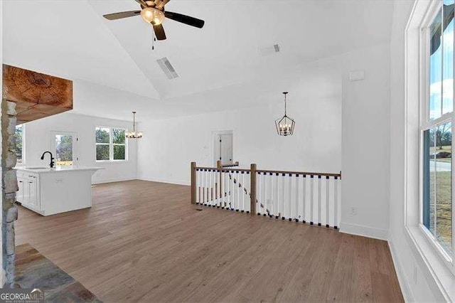 living room featuring lofted ceiling, sink, ceiling fan with notable chandelier, and dark wood-type flooring