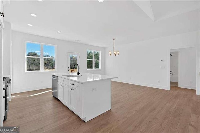 kitchen featuring white cabinetry, sink, hanging light fixtures, stainless steel appliances, and a center island with sink