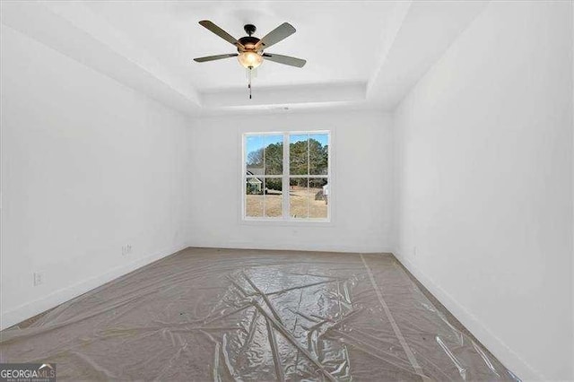 empty room featuring a raised ceiling and ceiling fan