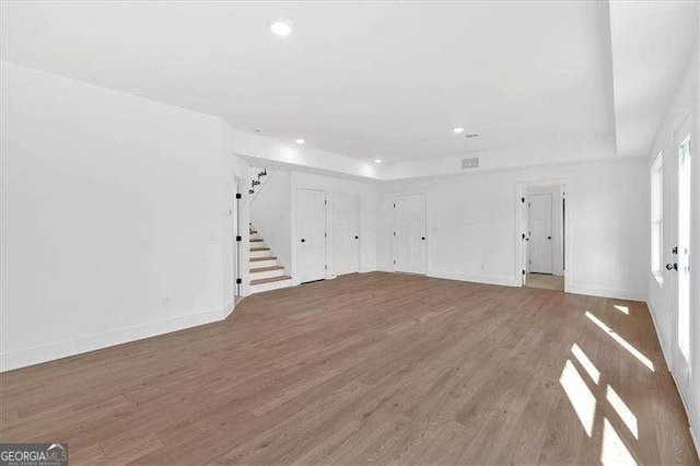 unfurnished living room featuring wood-type flooring and a raised ceiling