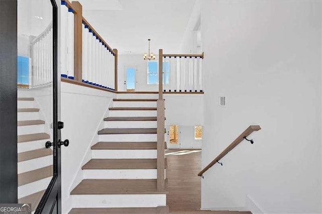 stairs with hardwood / wood-style floors and a notable chandelier