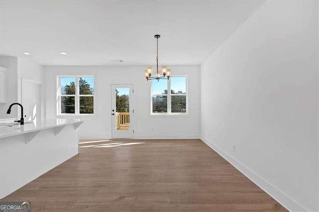 unfurnished dining area featuring sink, a notable chandelier, and dark hardwood / wood-style flooring