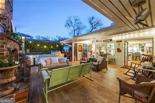 wooden terrace featuring exterior kitchen, a grill, an outdoor living space, and a ceiling fan