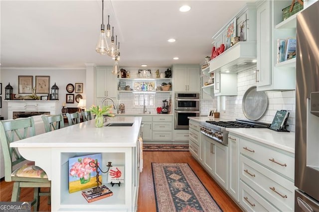 kitchen with a breakfast bar, wood finished floors, light countertops, appliances with stainless steel finishes, and open shelves