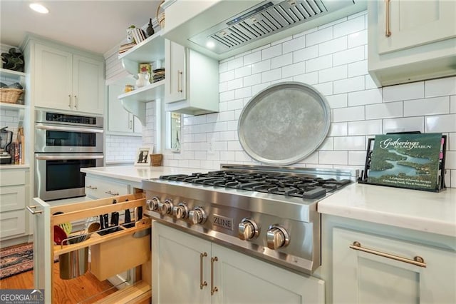 kitchen featuring open shelves, stainless steel appliances, tasteful backsplash, light countertops, and custom range hood