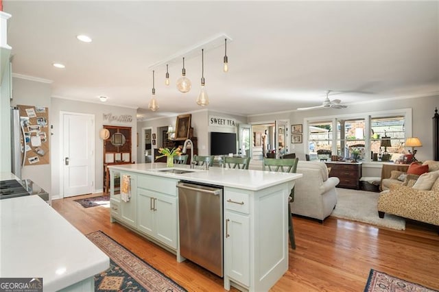 kitchen featuring stainless steel appliances, open floor plan, light countertops, and a sink