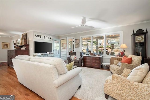 living room with ceiling fan, ornamental molding, wood finished floors, and baseboards