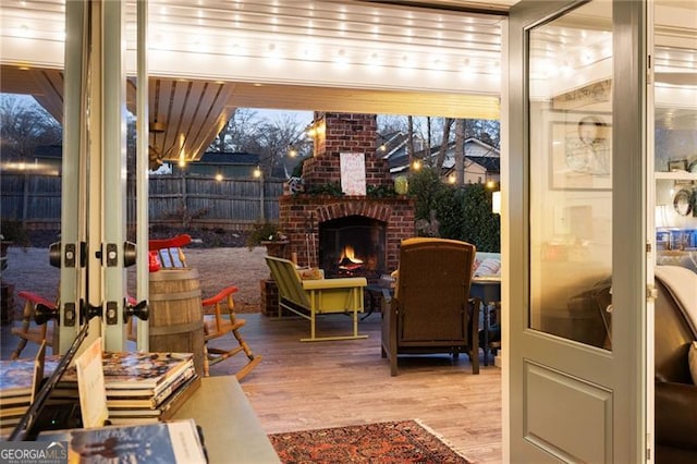 view of patio with a deck, an outdoor brick fireplace, and fence