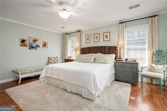 bedroom with visible vents, crown molding, and wood finished floors