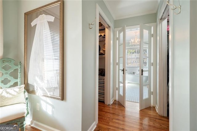 hallway featuring crown molding, baseboards, and wood finished floors