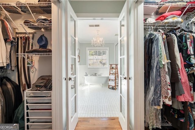 spacious closet featuring a chandelier, french doors, wood finished floors, and visible vents