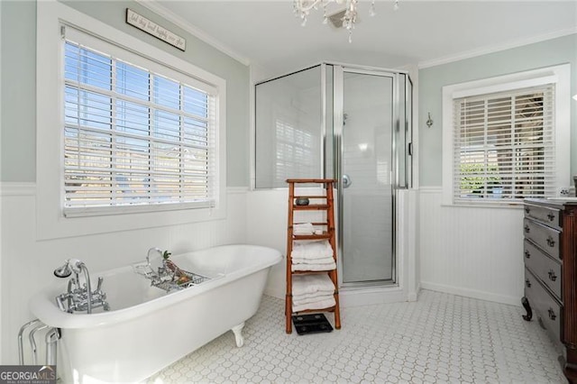 bathroom featuring a wainscoted wall, a shower stall, crown molding, and a soaking tub