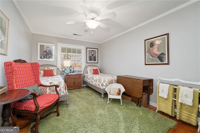 bedroom with ceiling fan, visible vents, crown molding, and wood finished floors