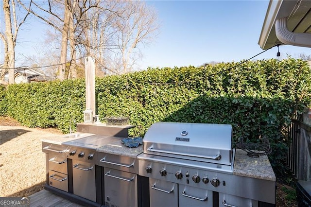 view of patio with a grill, an outdoor kitchen, and fence