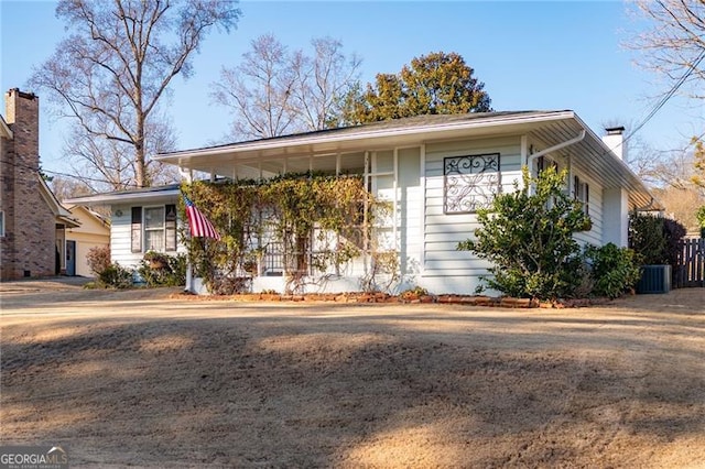 ranch-style house with central air condition unit, a chimney, and fence