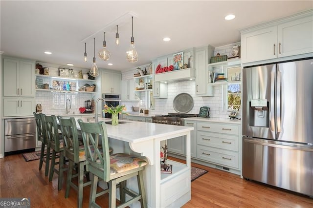 kitchen with open shelves, tasteful backsplash, light countertops, appliances with stainless steel finishes, and wood finished floors