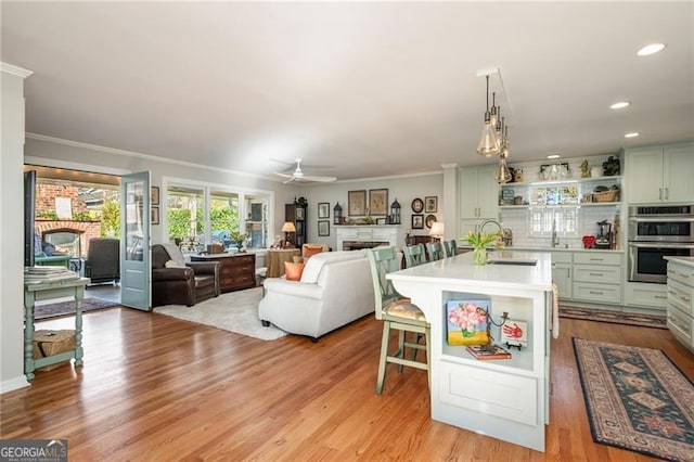 kitchen with double oven, a breakfast bar, a fireplace, light countertops, and open shelves