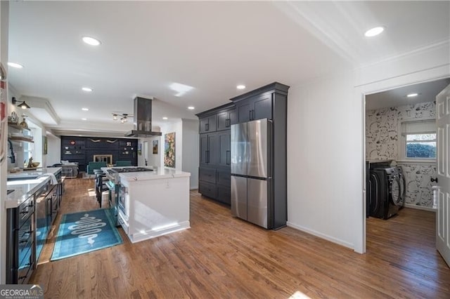 kitchen featuring stainless steel appliances, island exhaust hood, dark hardwood / wood-style floors, and washing machine and dryer