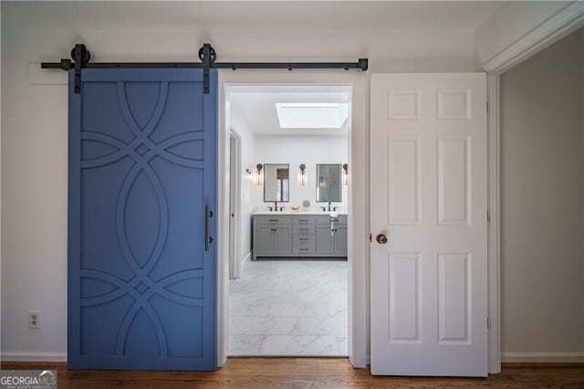 hall with wood-type flooring, a barn door, and sink