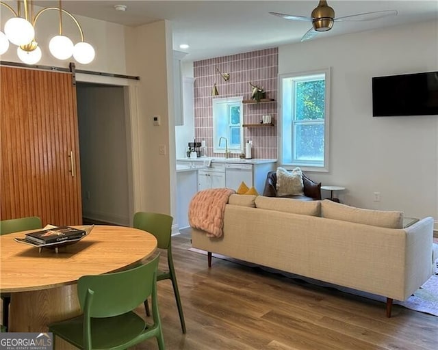 living room featuring ceiling fan, wood-type flooring, and a barn door