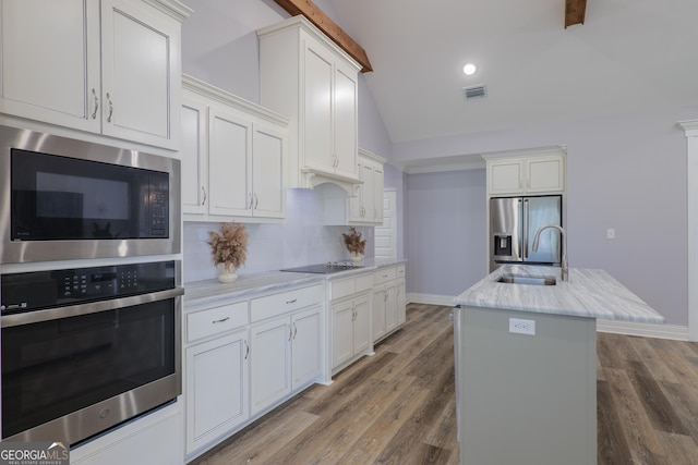 kitchen featuring appliances with stainless steel finishes, tasteful backsplash, white cabinetry, sink, and a kitchen island with sink