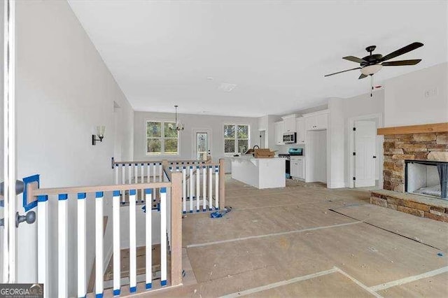 living room with ceiling fan with notable chandelier and a fireplace